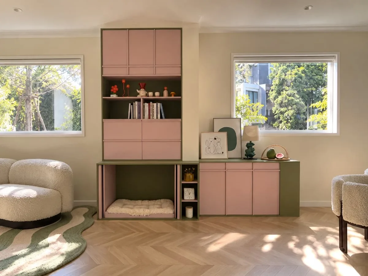 A pink and olive living-room wall with tall storage, open shelving, low cupboards and a cushioned resting bay